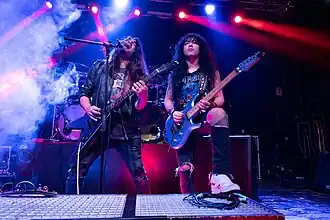 Two men playing guitars on stage