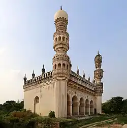 A very richly decorated mosque building, situated within a garden. The point-of-view is from the south-east, and it can be seen that the eastern facade of the mosque has five arched entrances and is elaborately decorated, as are the minarets. The southern wall is more plain, and is devoid of openings, except for a small window.