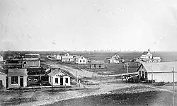 Black-and-white photo: ca. 20 one-story buildings on treeless prairie