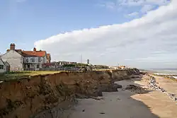 The precarious position of houses due to the effects of coastal erosion
