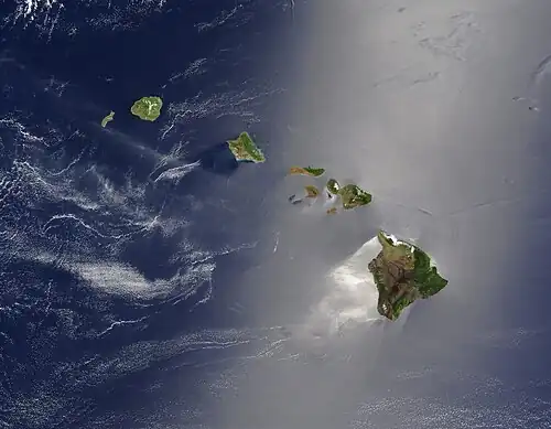 A satellite view of the Hawaiian islands, with the top of the image being North. There are few clouds, and most of the image is the seawater swirling in the wind, surrounding the islands.