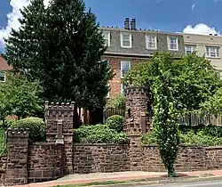 Brick wall and entrance gate with houses in the background