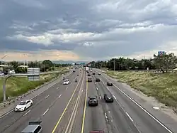 A six-lane freeway in a developed area with mountains in the distance.