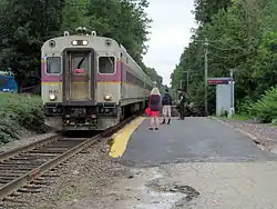 A passenger train stopped next to a small asphalt platform