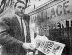 Black and white photo of Allen standing in front of a building labeled Wallace for President, holding papers