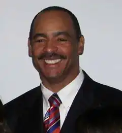 Kellen Winslow in a suit from about the shoulders up, smiling.