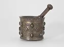 Mortar and pestle made of brass or quaternary copper alloy, piece cast, engraved, ringmatted and inlaid with silver, copper and a black compound.