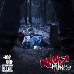 A man is lying in an open grave in a forest, gagged and tied, while looking at the person about to bury him alive.