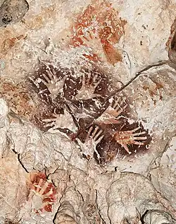 Le « Bouquet de mains », une manifestation remarquable de l’art rupestre de Bornéo, met en scène six mains dans une ronde graphique éternelle. A noter des mains de couleur rouge orangé plus anciennes recouvertes par le motif.