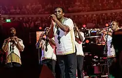 A group of performers on stage in matching outfits.