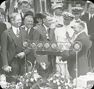 Lindbergh looks on as President Calvin Coolidge presents her son with the Distinguished Flying Cross (June 11, 1927)