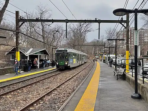 A light rail train at a station in a wooded area