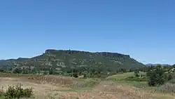 Lower Table Rock from across a field. Similar to Upper Table Rock, it rises steeply to its very flat top.