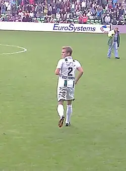 Back view of a fair-haired white man wearing sports kit on a field