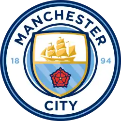 A rounded badge depicting a shield containing a ship, the Lancashire Rose, and the three rivers of Manchester.