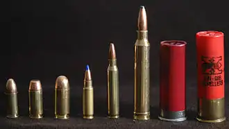 Photo of various cartridges, showing from left to right: 9×19mm Parabellum, .40 S&W, .45 ACP, 5.7×28mm, 5.56×45mm NATO, .300 Winchester Magnum, 2.75-inch 12 gauge, and 3-inch 12 gauge