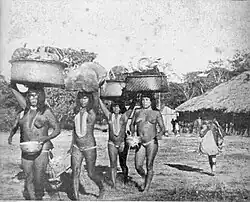 Four woman in traditional garments are seen carrying things