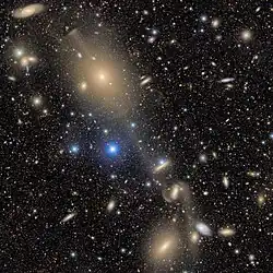 NGC 4261 is the large elliptical galaxy at the top of the image.