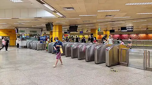 Concourse level with fare gates dividing the unpaid and paid areas of the station. A rainbow dressing of 15,000 coloured tiles is displayed along the concourse in the background.