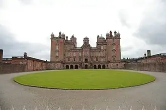 View of the front of Drumlanrig Castle, looking slightly up, standing near the fencing separating the castle itself from the public