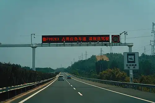 A "name-and-shame" variable message sign along the G18 Expressway in Shandong, China, which displays the licence plate numbers of offending motorists, along with the traffic infractions they've committed. In this example, the sign reads "鲁F982EX: Occupying the emergency lane, please drive according to the rules".