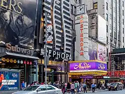 The facade of the theater as seen from across the street. The musical Aladdin is being advertised on the marquee.