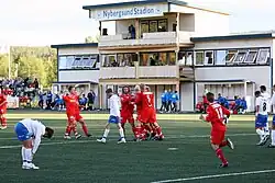 Two football teams in a stadium, the away team celebrating