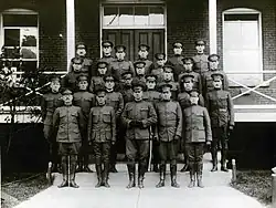 Black and white photo of men in uniform standing on stairs