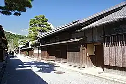 Two storied wooden houses next lining a street.