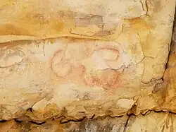 A pictograph of a human figure floating over a cross-in-circle.