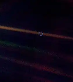A tiny, pale blue dot is contrasted against the vastness of space