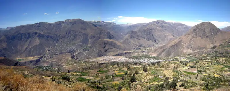 Panoramic view of an Andean canyon with cliffs and terraced farmland under a clear sky