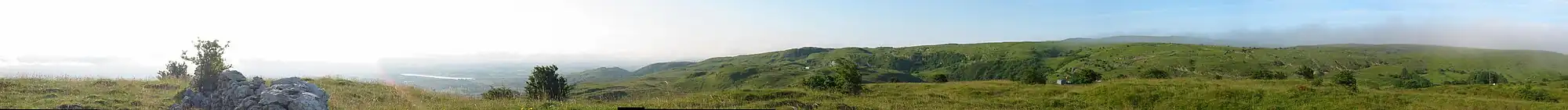 Panorama of grassy hills interspersed with limestone features and farm tracks.