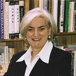 Portrait photo of a gray-haired woman standing in front of a book shelf filled with books.