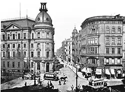 A black and white photograph of 1892 of a city street crossing, with 2 rows of houses.
