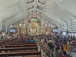 Church interior in 2023. Devotees in the central aisle are seen walking on their knees towards the sanctuary, offering prayers.