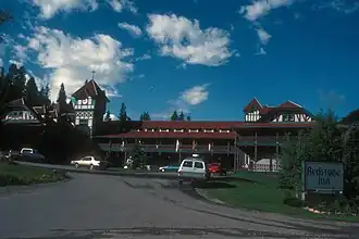 An ornate two-story building with a central clock tower and red roof in the rear of the left side of the image. On the right is a large sign in the foregrounds with "Redstone Inn" in large gothic letters, "Historic Landmark" in smaller type above it, and "Restaurant & Bar" below