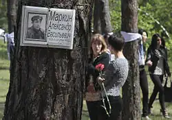 People with flowers near a tree with a sign