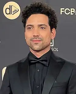 close-up of Rafael Morais wearing a black shirt, jacket, and bowtie, looking just right of camera with slight smile
