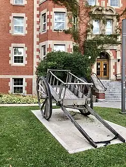 Cart on concrete pad in lawn in front of a brick building