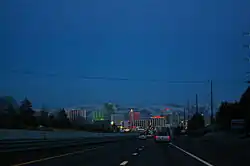 Dusk view of a freeway descending into a neon lit cityscape