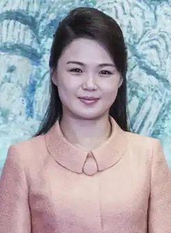 Ri Sol Ju smiling against a blue background at a summit, 2018