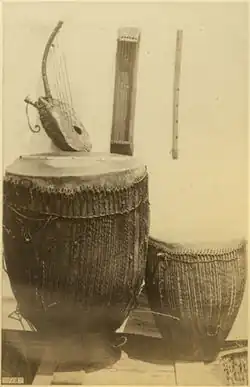 South Sudan or Northern Uganda. Acholi people, type D trough zither (center back), arched harp (left), unnamed flute (right). Circa 1880. The zither is a nanga or possibly kinanda.