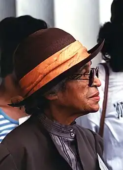 A profile photograph of Rosa Parks as an older woman, wearing sunglasses and a brown hat.