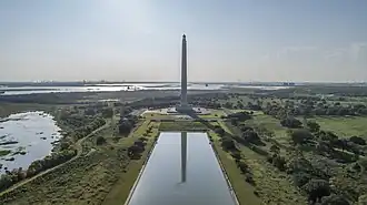 A tall monument with a star at the top in front of a reflection pool