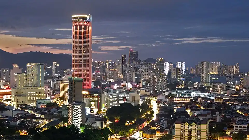 A panoramic view of the city skyline, dominated by high-rise housing and skyscrapers, at dusk.