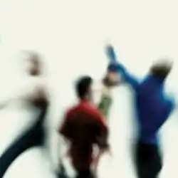 A blurry photo of the four band members in motion, in front of a white background.