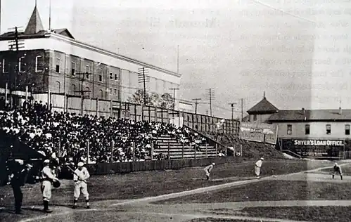 A black and white photograph of home plate and left field bleachers at a ballpark