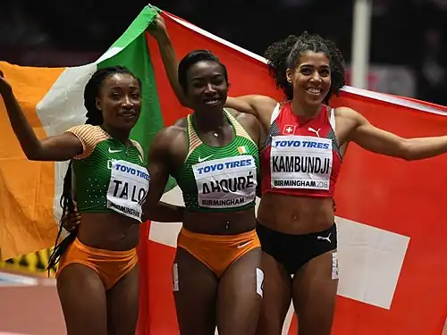 Ta Lou holding up the Ivorian flag, next to two other athletes