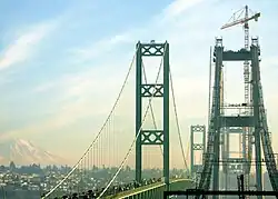 Tacoma Narrows Bridge, during the construction of the eastbound span, as seen from the Kitsap Peninsula in December 2005, with Tacoma and Mount Rainier visible in the background.
